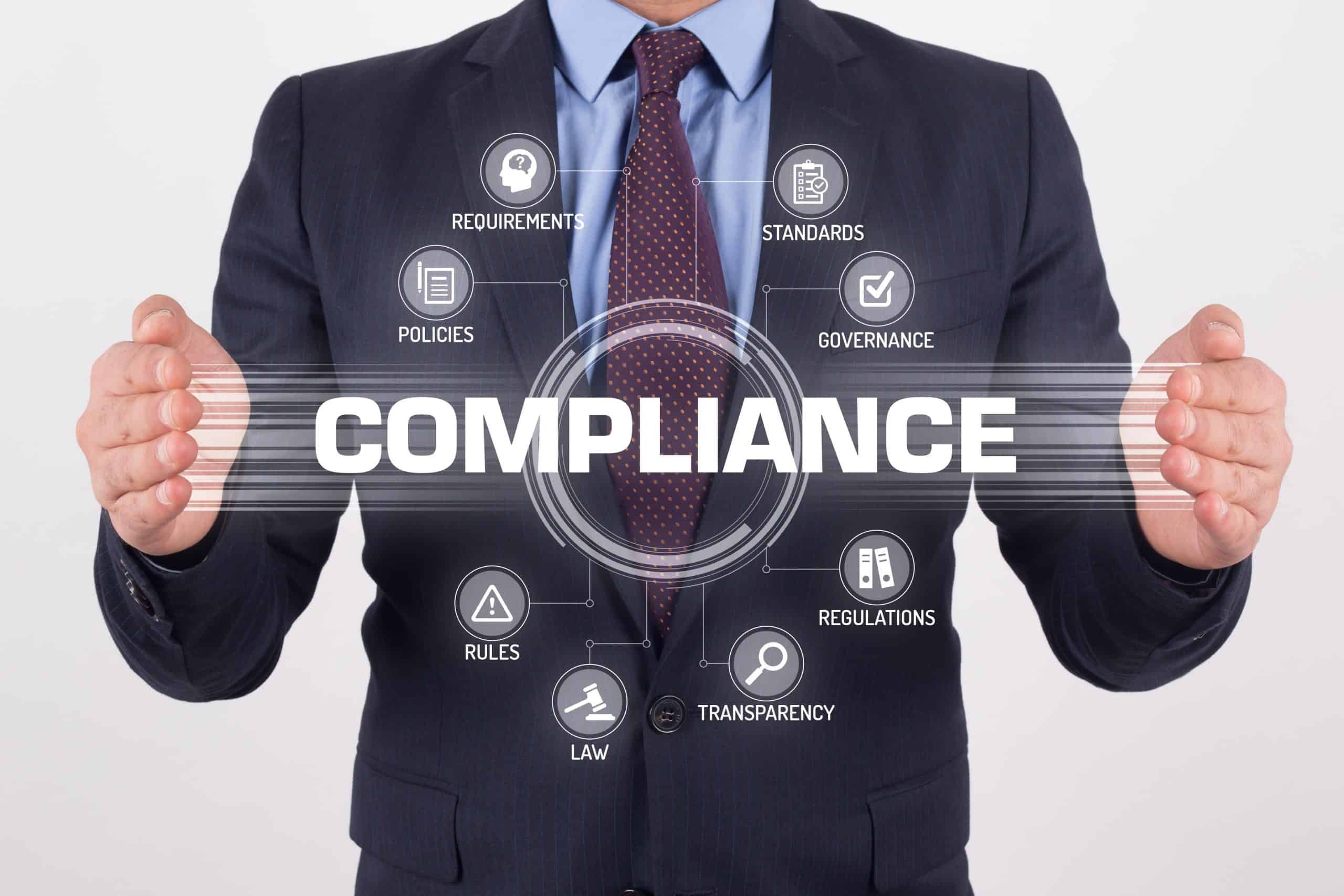 Let's talk A man in a suit holding up the word compliance.