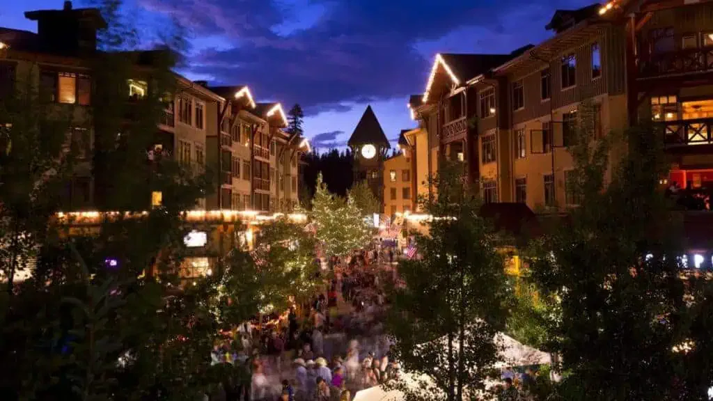A street with many people walking around at night in Mammoth Lakes.