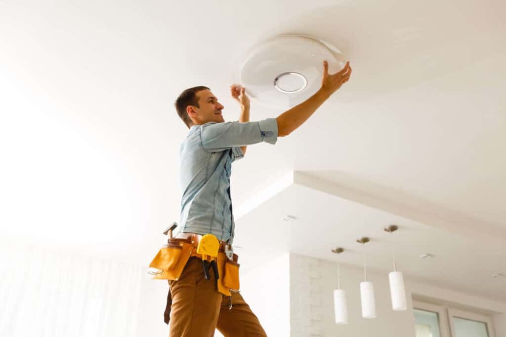 Let's talk A man performing property management tasks in a home in Mammoth Lakes, including installing a ceiling fan.
