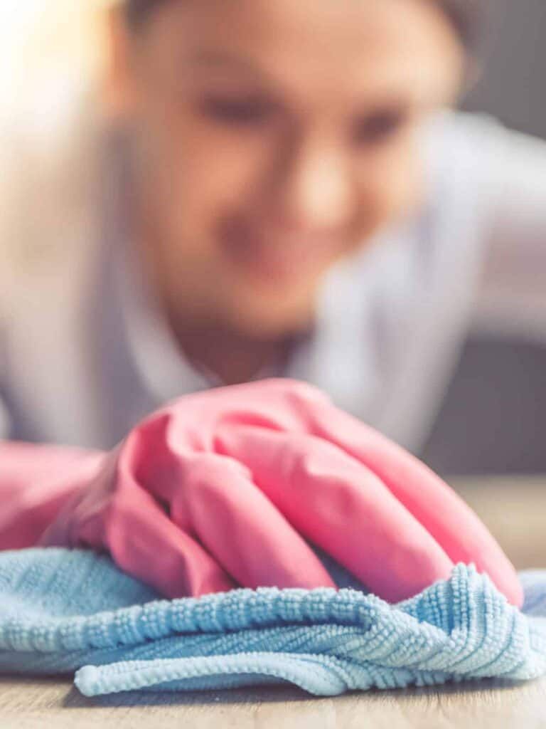 Let's talk A woman in pink gloves cleaning a cloth on a table in a property management setting.