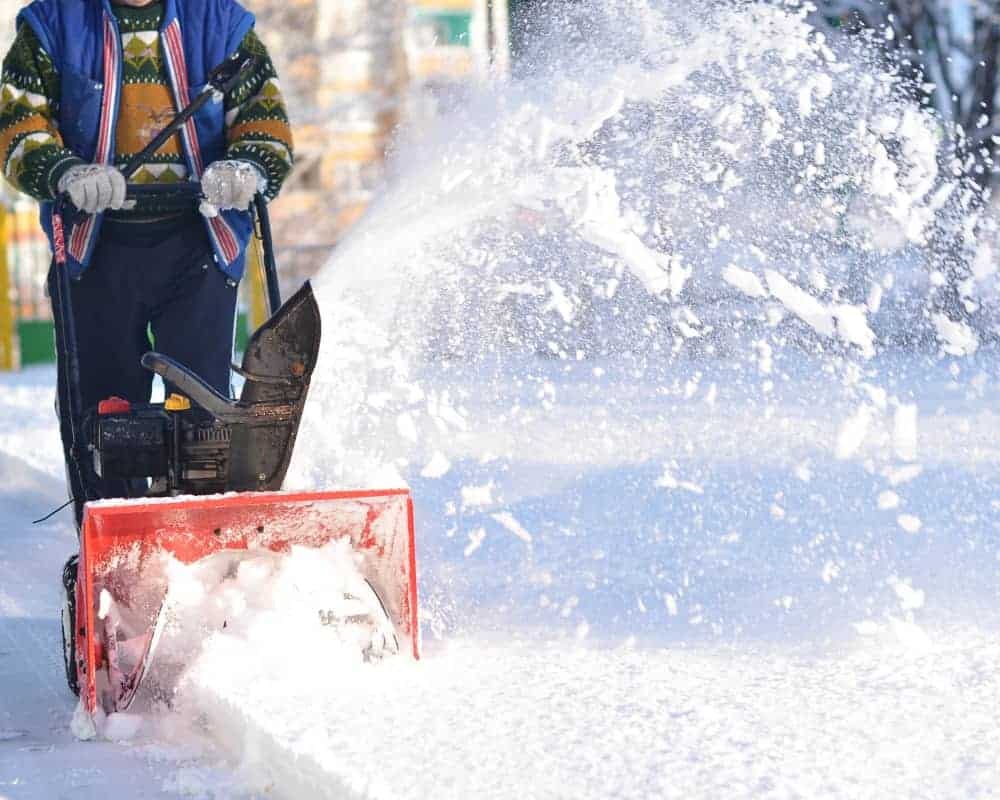 A man using a snow blower in the snow.