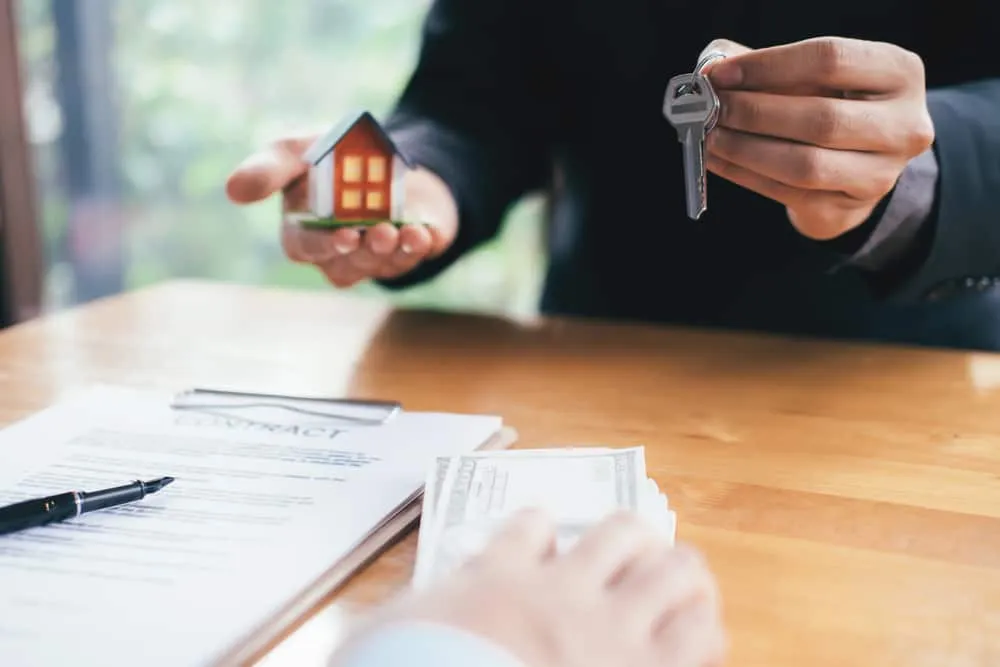 A man is holding a key to a house model.