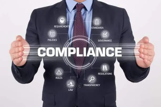 A man in a suit holding up a screen with the word compliance.