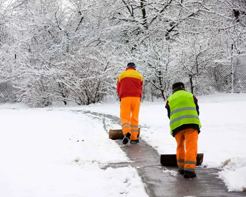 Two men shoveling snow in a park.